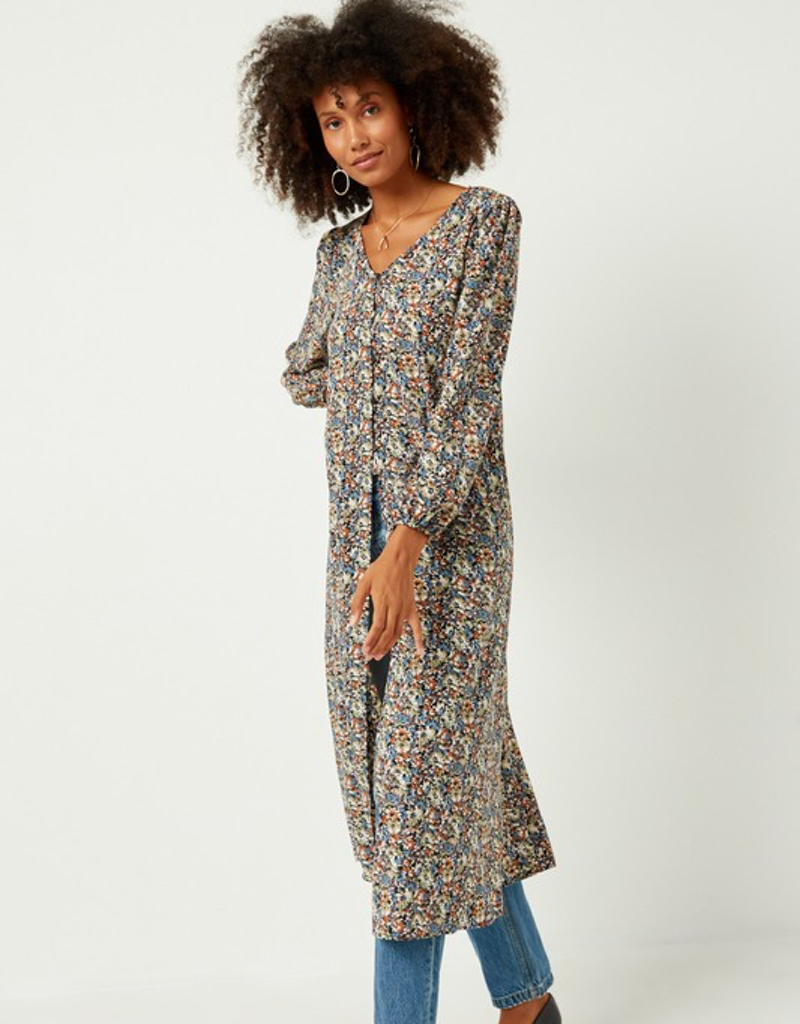 Woman wearing a floral print floor-length duster with puff sleeves in rust, blue, and cream colors.