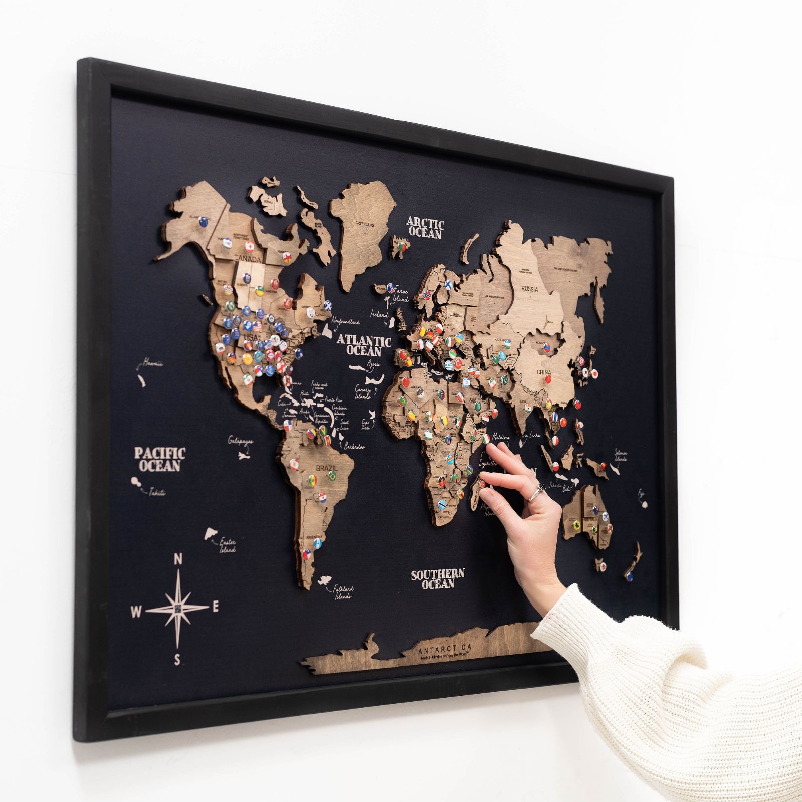 3D wooden world map panel in black, white, and ocean colors