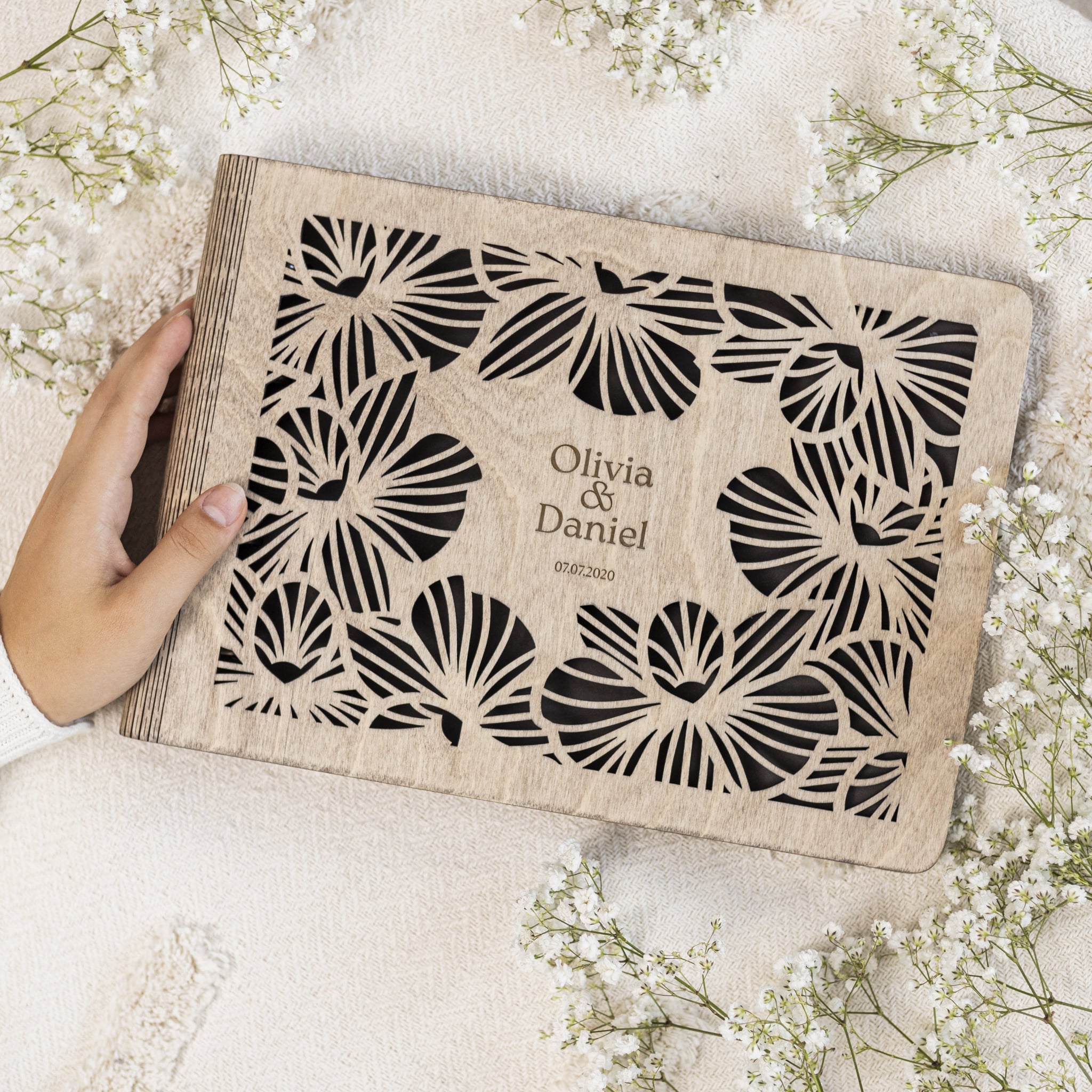 Close-up of Orchid Wooden Photo Album with floral engraving and tie closure in a modern living room setting.