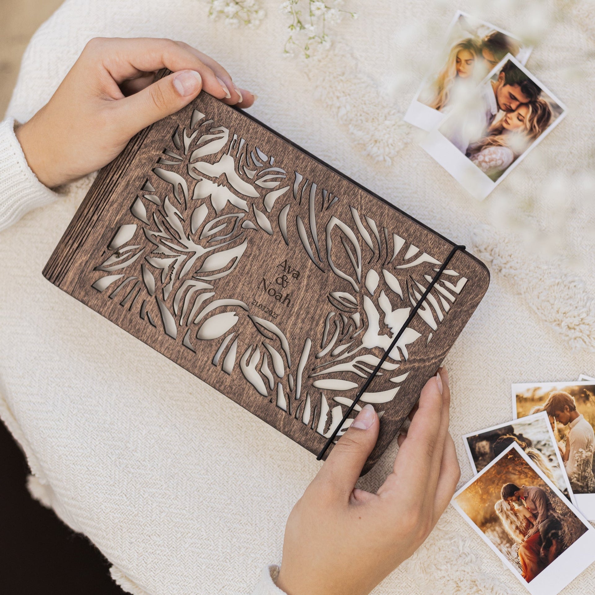 Close up of a rustic wooden photo album with engraved wildflower floral pattern and cream paper interior.