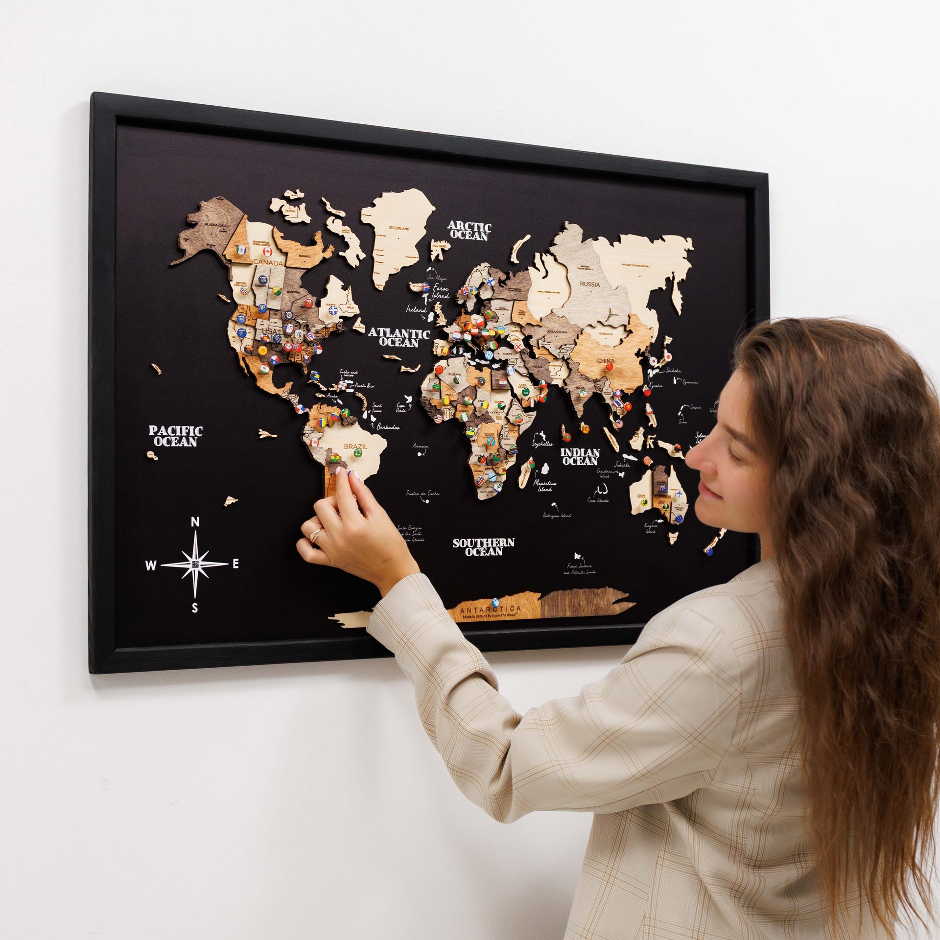A decorative 3D wooden panel world map featuring brown, beige, and black tones on a living room wall.