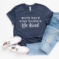 Heather navy unisex crew neck graphic tee with the quote Work Hard Stay Humble Be Kind in white text, laid out with blue jeans and white sneakers.