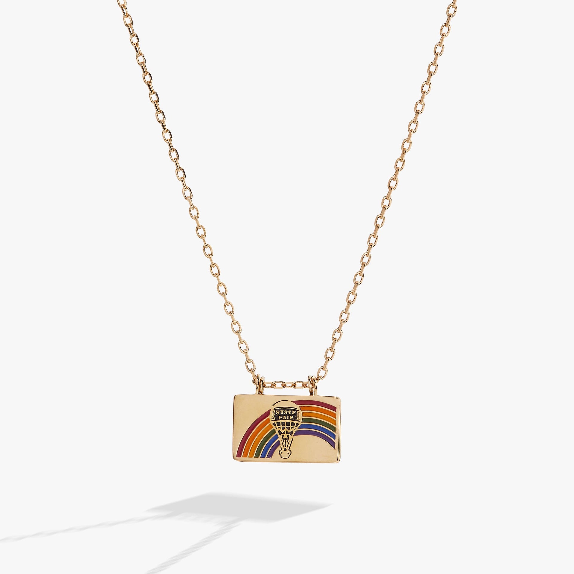 The Wizard of Oz flip-open charm necklace featuring a rainbow, hot air balloon, and the quote There's no place like home.