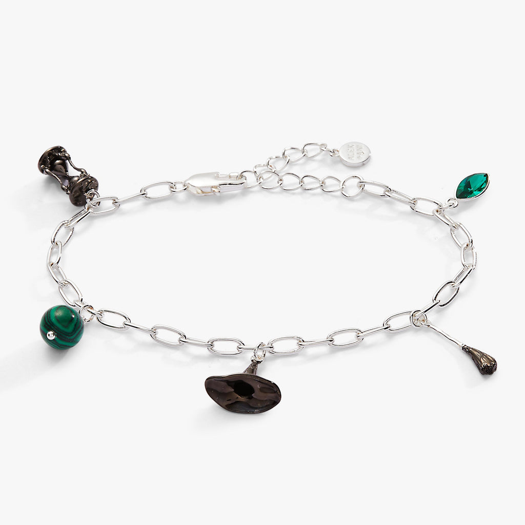 Silver-tone charm bracelet featuring Wizard of Oz Wicked Witch charms including a hat, broom, and green crystal
