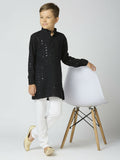 A young boy wearing a black full sleeves cotton kurta and pyjama set with elegant sequin detailing.