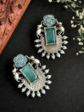 A pair of large, vibrant C Green Monalisa stone stud earrings featuring intricate brass craftsmanship.
