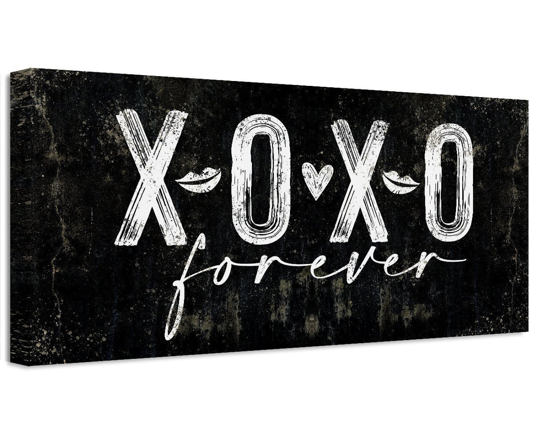 A black and white canvas print displaying XOXO Forever text, hanging above a bed as wall decor.