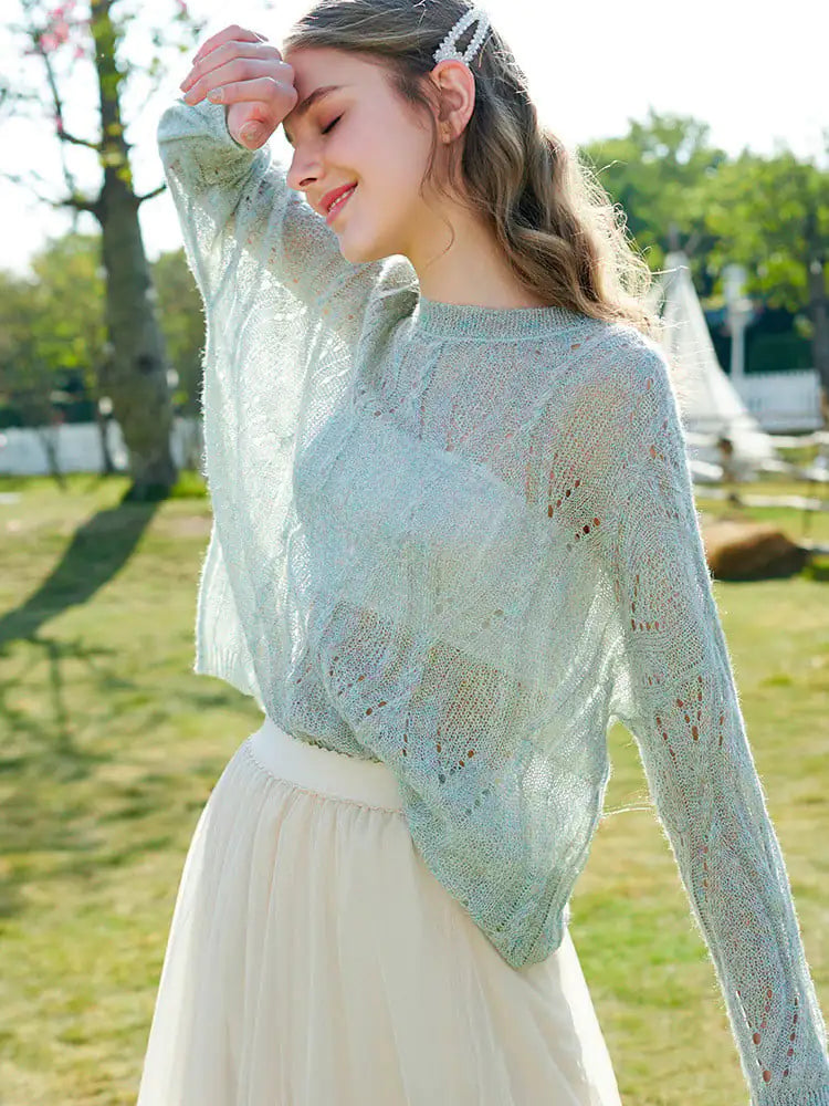 A woman wearing a soft light blue hollow knit long-sleeve sweater with a crew neckline.