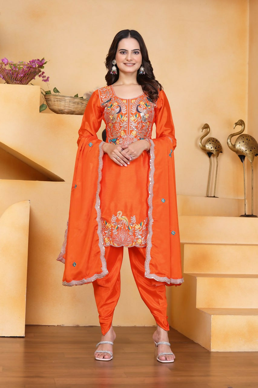 Woman wearing an orange silk embroidered kurti and dhoti pant set with a matching dupatta