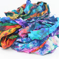 Vibrant tie-dyed sari silk ribbon yarn in jewel tones of blue, magenta, and ochre with organic, chunky texture.