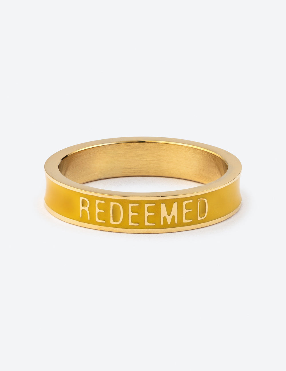 A close-up shot of a gold tone ring with a yellow enamel band featuring the word REDEEMED in white, held by a person.