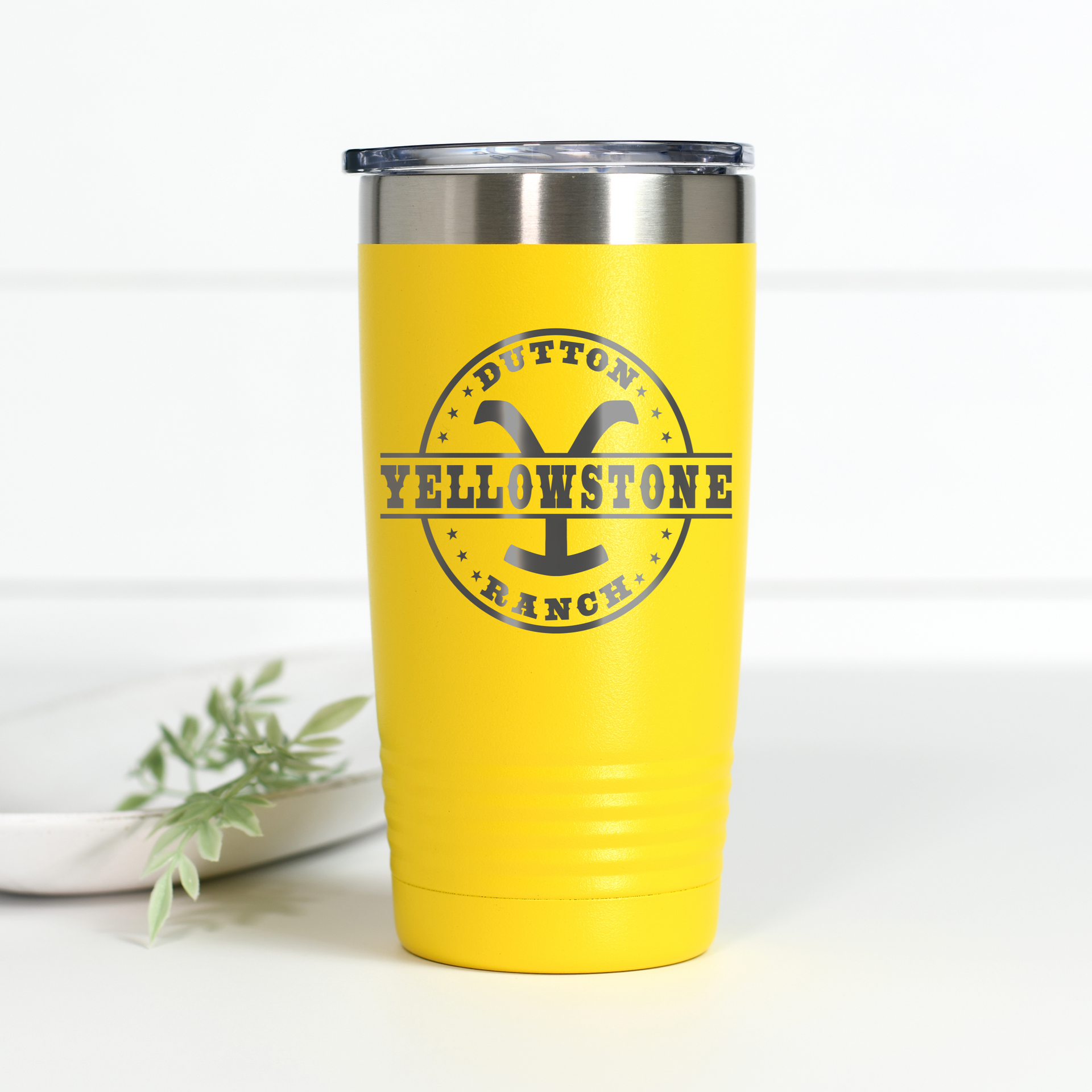 A yellow 20 oz stainless steel tumbler featuring the Yellowstone Dutton Ranch logo laser-engraved on the front.
