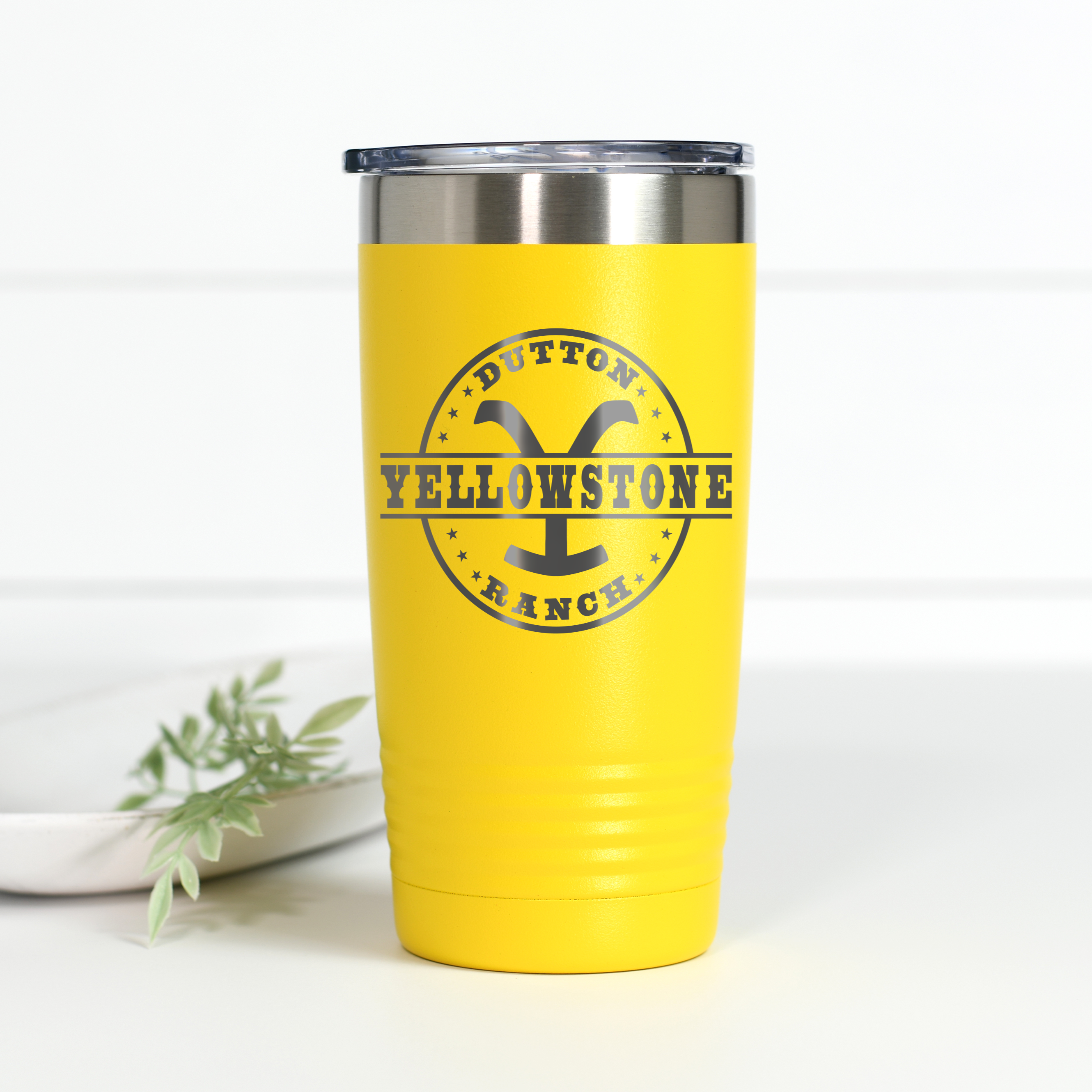 A yellow 20 oz stainless steel tumbler featuring the Yellowstone Dutton Ranch logo laser-engraved on the front.