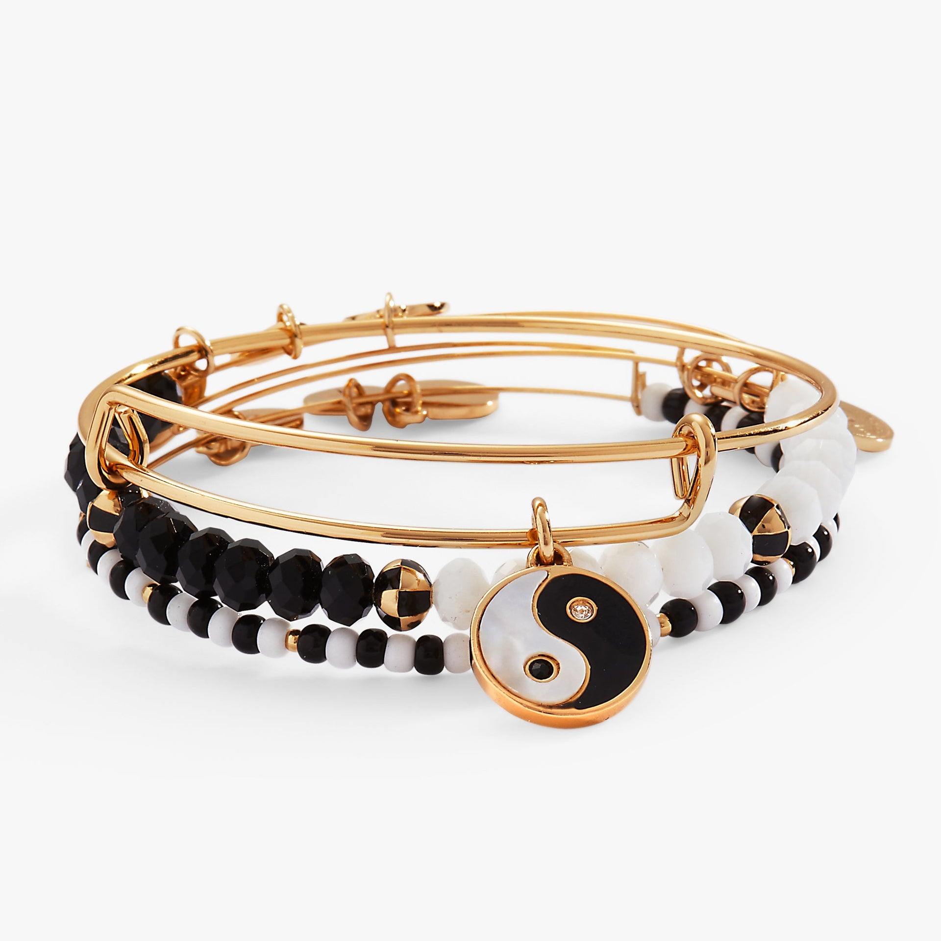 A set of three Alex And Ani bangles featuring a yin yang charm with mother of pearl and enamel accents.