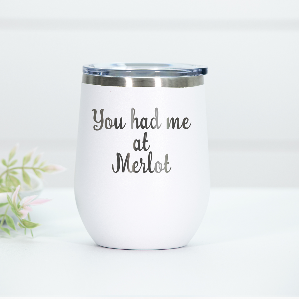 White stainless steel wine tumbler with the phrase 'You had me at Merlot' laser engraved on the front, featuring a clear lid.