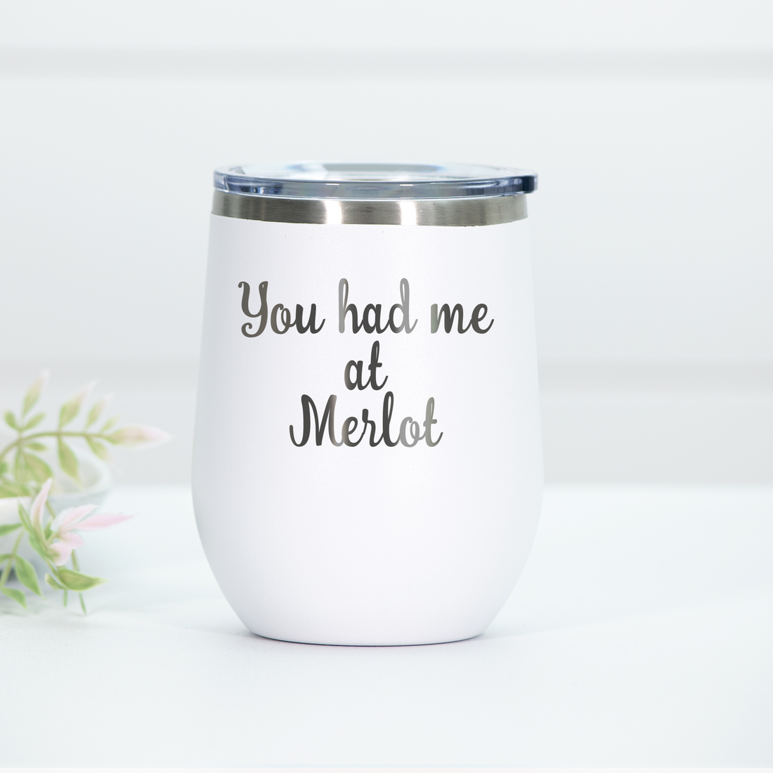 White stainless steel wine tumbler with the phrase 'You had me at Merlot' laser engraved on the front, featuring a clear lid.