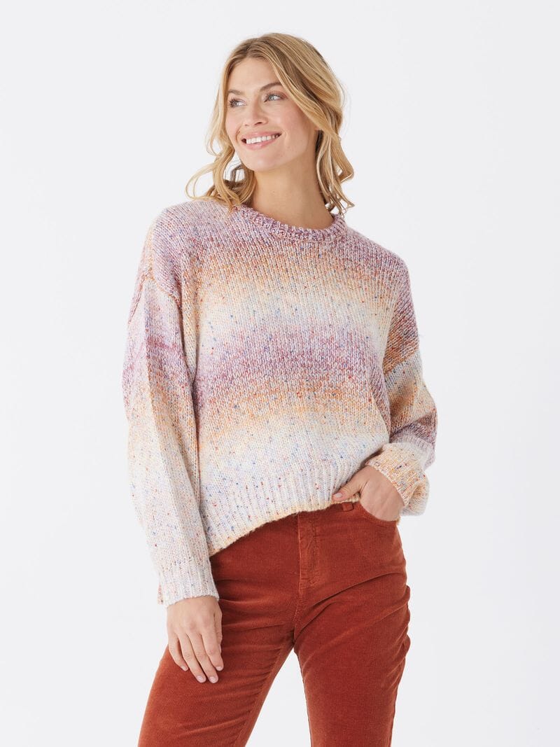 Woman wearing a purple, orange, and white gradient drop-shoulder sweater knit pullover.